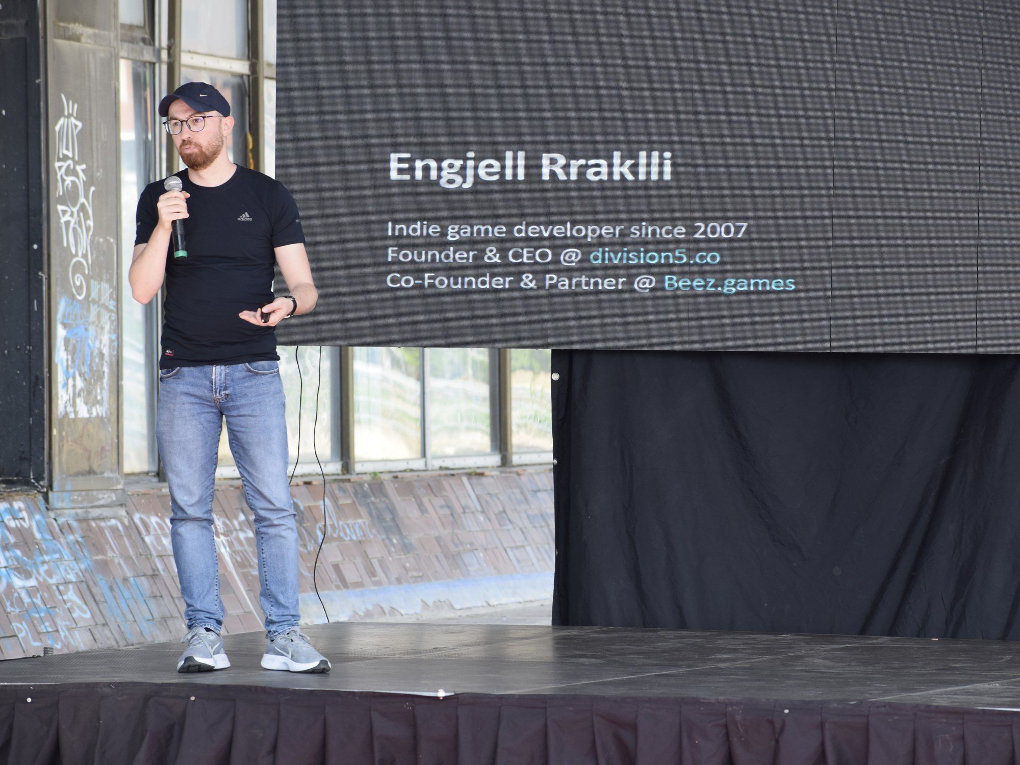 Engjell Rraklli on stage beside his speaker slide